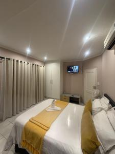 a bedroom with a large white bed with a tv on the wall at Green Grove Villa in Centurion