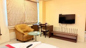 a living room with a chair and a television at Hotel Rajdoot Royale by Ambai in Ichalkaranji