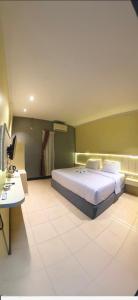a bedroom with a large bed and a desk at Hotel Mario Parepare in Parepare