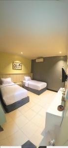 a hotel room with two beds and a desk at Hotel Mario Parepare in Parepare