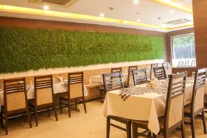 a restaurant with tables and chairs and a green wall at Hotel Rajdoot Royale by Ambai in Ichalkaranji