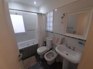 a white bathroom with a toilet and a sink at Habitación en casa familiar "FILOMENA" in Puerto Madryn