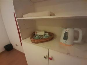 a kitchen cabinet with a coffee maker and two tea cups at Habitación en casa familiar "FILOMENA" in Puerto Madryn