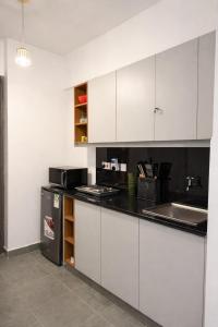 a kitchen with white cabinets and a black counter top at The Cozy Cube at Tsavo Sunset in Nairobi