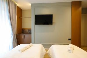 two beds in a room with a tv on the wall at Dion Boutique Hotel - City Center in Krujë
