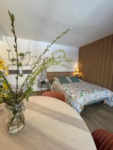 a bedroom with a bed and a table with a vase of flowers at Le Charme du Gaschney in Muhlbach-sur-Munster