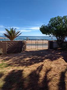 a view of a beach with a fence and trees at Lighthouse Studio in Doring Bay
