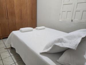 a white bed with two towels on top of it at Casa simples e funcional in Aimorés