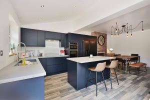 a kitchen with blue cabinets and a table with chairs at Spacious Gate 3BR City 5mins Walk Pets Welcome in Hereford