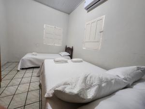 two beds in a room with white walls at Casa simples e funcional in Aimorés +8 photos