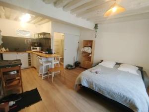 a bedroom with a bed and a desk and a kitchen at Le Petit Cocon d'Orléans in Orléans