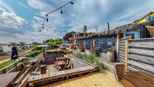 a deck with a table and chairs and a building at Aux 4 vents - Auberg'Inn in Carleton-sur-Mer
