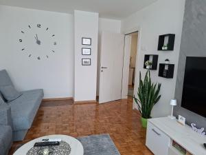 a living room with a couch and a clock on the wall at Luna apartman in Čačak