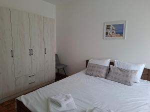 a bedroom with a white bed and a cabinet at Luna apartman in Čačak