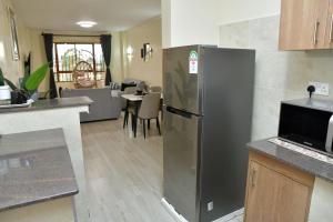 a kitchen with a stainless steel refrigerator and a living room at Nivaro Homes in Nakuru