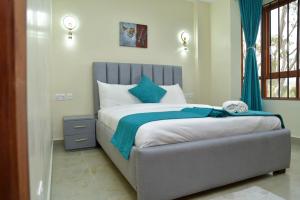 a bedroom with a large bed with a blue blanket at Nivaro Homes in Nakuru +12 photos