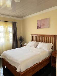 a bedroom with a large bed with white sheets at Indolo Home in Bulawayo