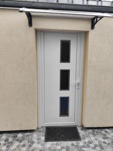 a white door on the side of a building at Charmant Studio indépendant in Louvres
