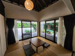 a living room with a table and chairs and windows at Private Villas Ryuz備瀬 in Motobu