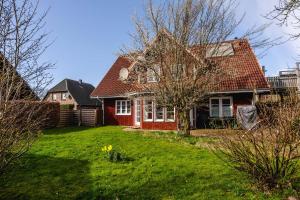 a red house with a tree in a yard at Odin in Goltoft