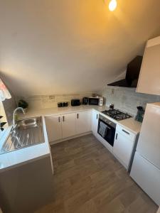 a small kitchen with white cabinets and a sink at Elegant Flat in Ealing in Greenford
