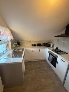 a small kitchen with white cabinets and a sink at Elegant Flat in Ealing in Greenford