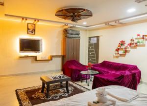 a room with a bed and a couch and a tv at X Western Hills panchagani in Panchgani