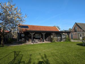 a large house with a patio and a grass yard at The Bee - Trekkershuts & Apartment in Opperdoes