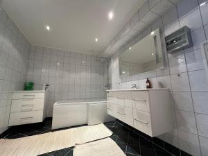 a bathroom with a tub and a sink and a mirror at Apartments with Panoramic Views in Longyearbyen +20 photos