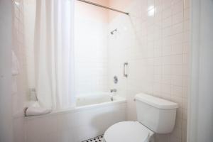 a white bathroom with a toilet and a bath tub at Curry Mansion Inn in Key West