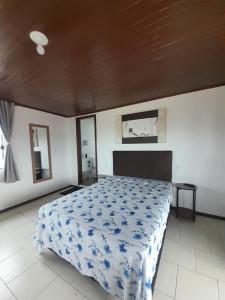 a bedroom with a bed with a blue and white blanket at Studio Duplex Praia do Porto in Imbituba