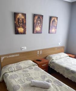 a room with two beds and three pictures on the wall at Coalla Rooms Luxe in Lugones