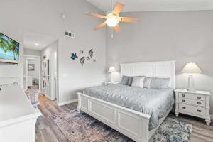 a bedroom with a white bed and a ceiling fan at St Augustine Beachfront Condo with Ocean Views in Saint Augustine Beach