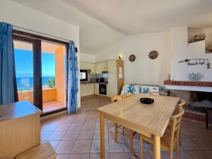 a living room with a table and a kitchen with a view at Residence Il Borgo di Porto Corallo in Villaputzu