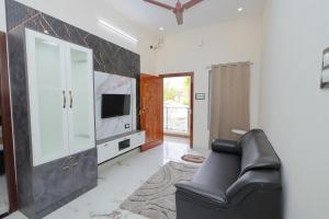a living room with a black leather couch and a tv at MK service apartment in Tirunelveli