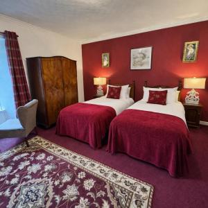 two beds in a hotel room with red walls at Killean Farmhouse B&B in Inveraray