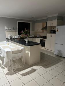 a kitchen with white appliances and a white table and chairs at Coomera Private Rooms near DreamWorld in Gold Coast