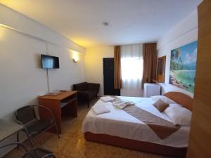 a hotel room with a bed and a chair at Casa Paloma in Costinesti