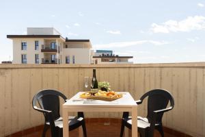 a table with a bottle of wine and a bowl of fruit at Milano Lux Apartament - Private Indoor Parking in Sesto San Giovanni