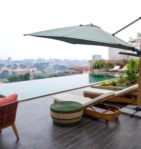 a patio with an umbrella and chairs on a roof at KÓLÒ Hôtel in Yaoundé