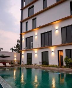 a building with a swimming pool in front of a building at KÓLÒ Hôtel in Yaoundé