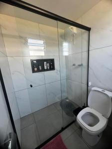 a bathroom with a toilet and a glass shower at Chalé Rosa dos Ventos in Itapoa +44 photos