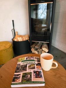 a cup of coffee and a magazine on a table with a cup of coffee at Slow Stay Coo in Stavelot