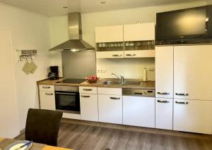 a kitchen with white cabinets and a sink at Ferienwohnung Moselblick in Ediger-Eller +10 photos