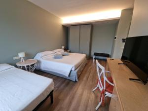 una camera d'albergo con due letti e una TV a schermo piatto di City Hotel a Senigallia