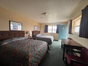 a hotel room with two beds and a desk at Cherokee Inn in Cherokee