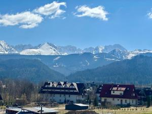 a group of houses with mountains in the background at Karczma Mikuda - Sauna Basen Jacuzzi z widokiem na góry - Kuligi - Parking in Zakopane