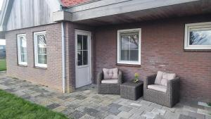 two wicker chairs sitting on a patio next to a house at 't Olde Land in Den Burg