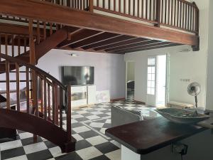 a living room with a staircase and a checkered floor at Maison Belle Vue in Le Robert