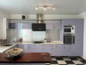 a kitchen with white cabinets and a table in it at Maison Belle Vue in Le Robert
